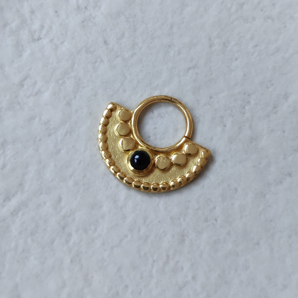 Large gold septum with black onyx, displayed on a jewelry plate.