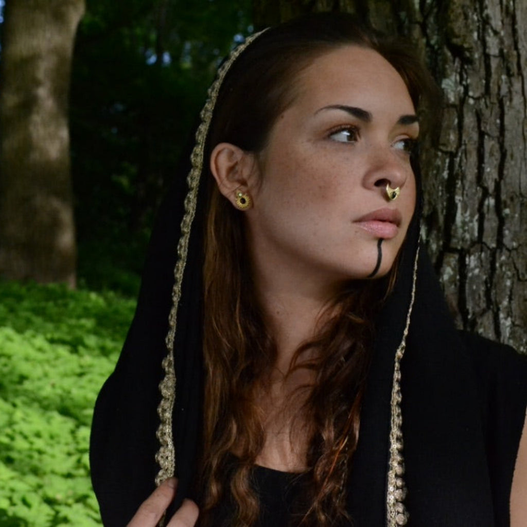 A model wearing a v-shaped gold septum nose ring with black onyx.