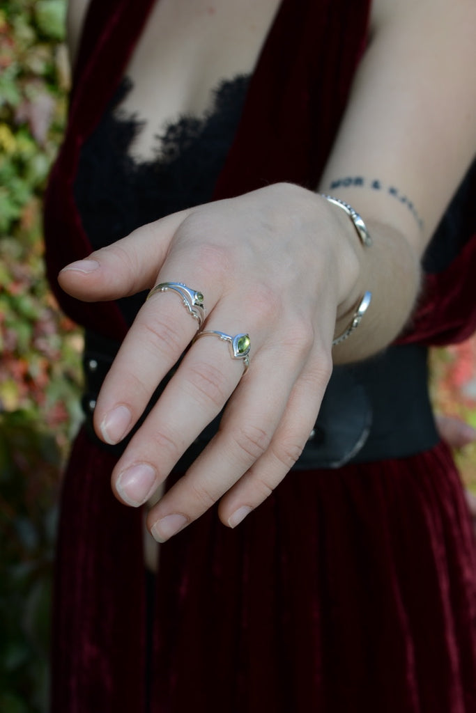 Close-up of a hand wearing multiple silver rings with a blurred background