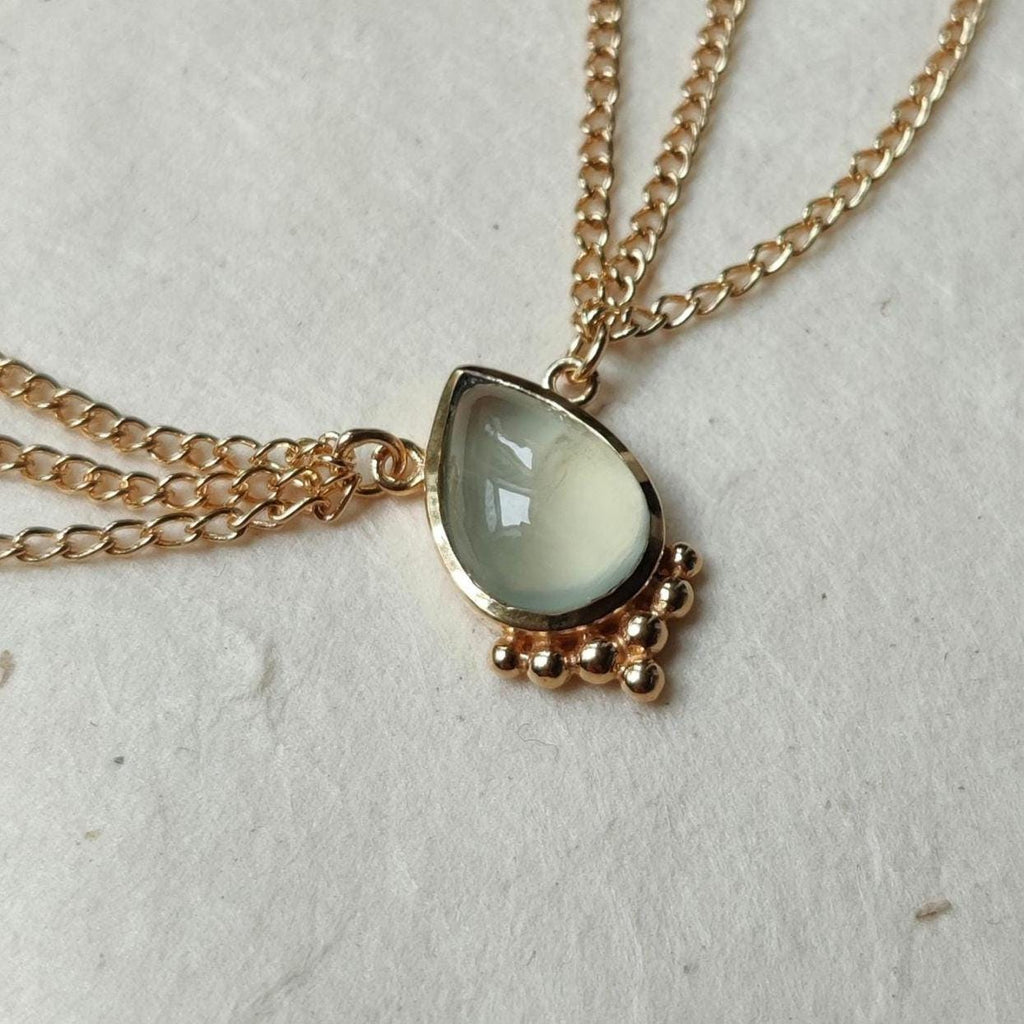 Gold head chain with drop-shaped green prehnite centerpiece, and three chains draping on each side.