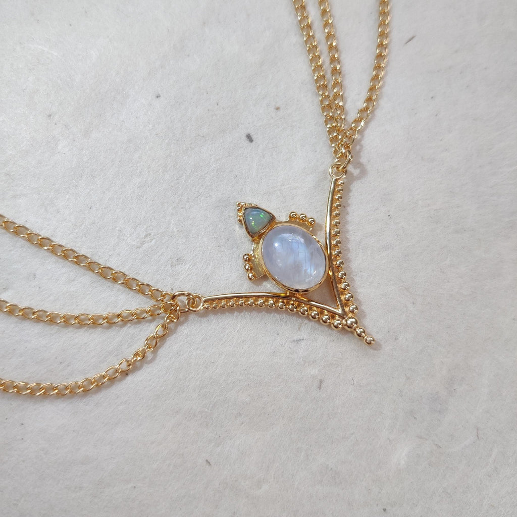 Gold head chain with moonstone and opal, with a v-shaped design and three chains draping from the sides.