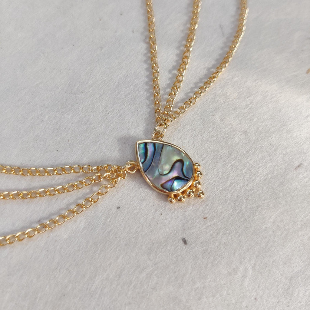 Gold head chain with drop-shaped abalone shell centerpiece, and three chains draping on each side.