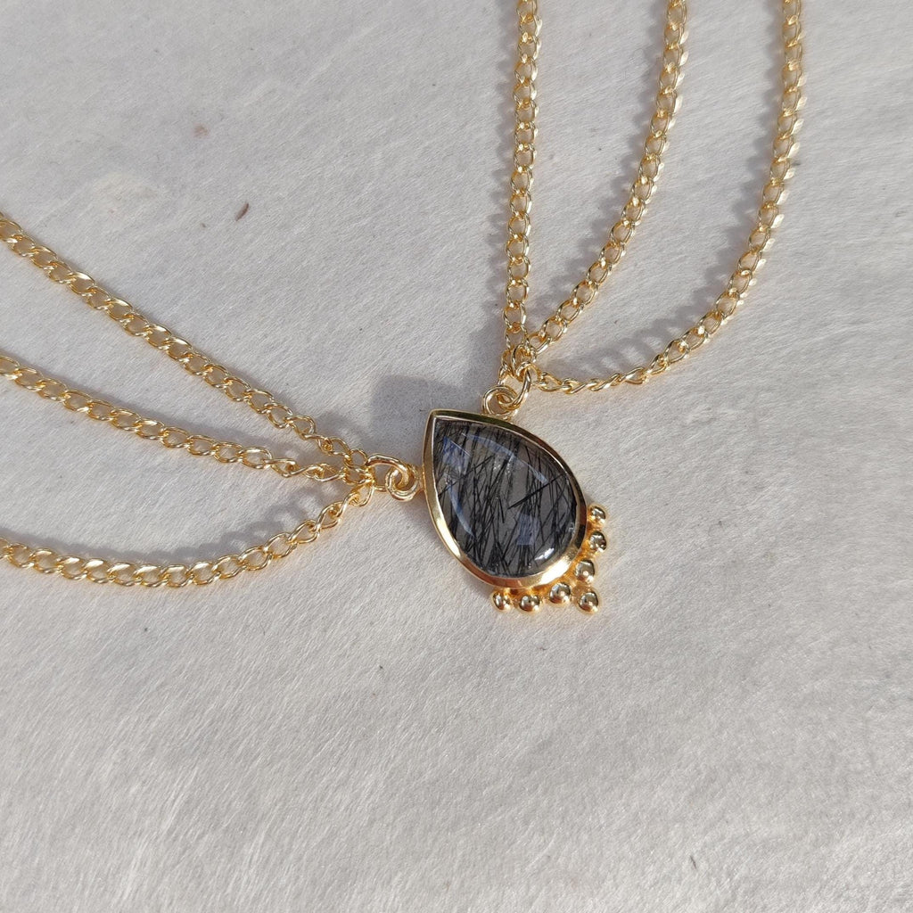 Gold head chain with drop-shaped rutile quartz gemstone centerpiece, and three chains draping on each side.