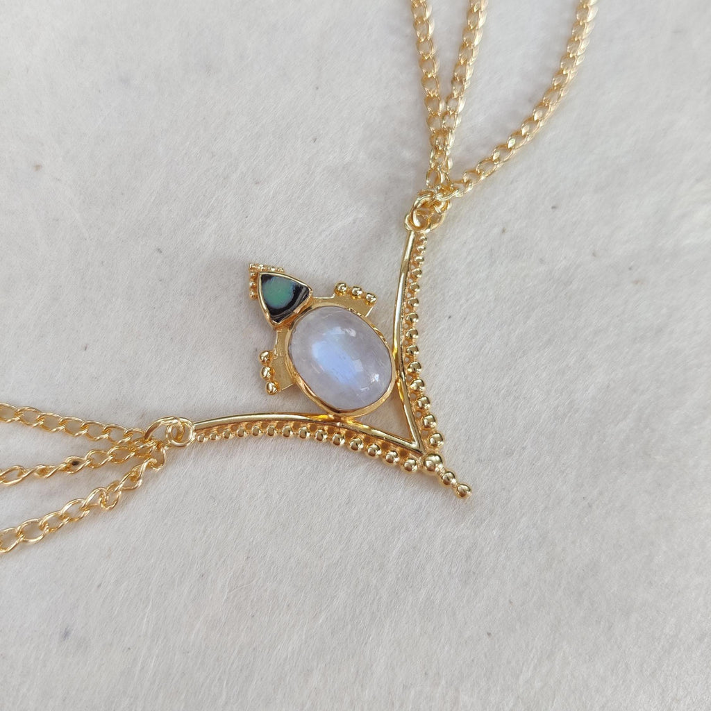 Gold head chain with a v-shaped centerpiece adorned with moonstone and abalone shell.