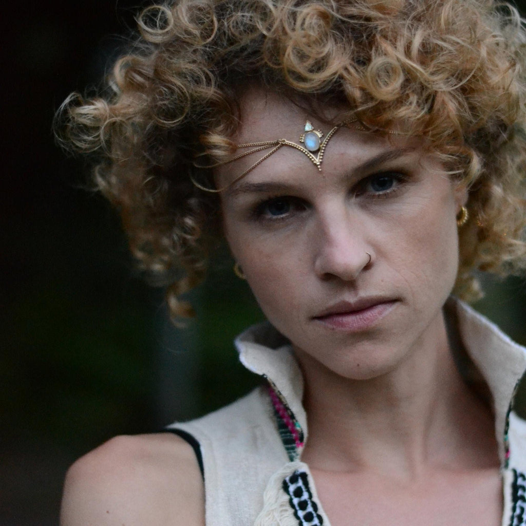 A model wearing a moonstone head chain in gold, with a v-shaped design and three chains draping on the forehead.