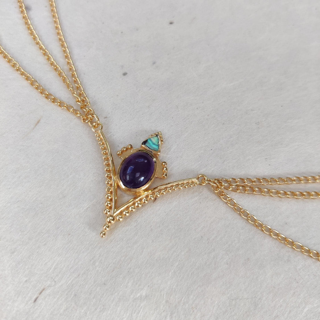 Gold head chain with purple amehyst and abalone shell. The design is v-shaped, with three chains draping from each side.