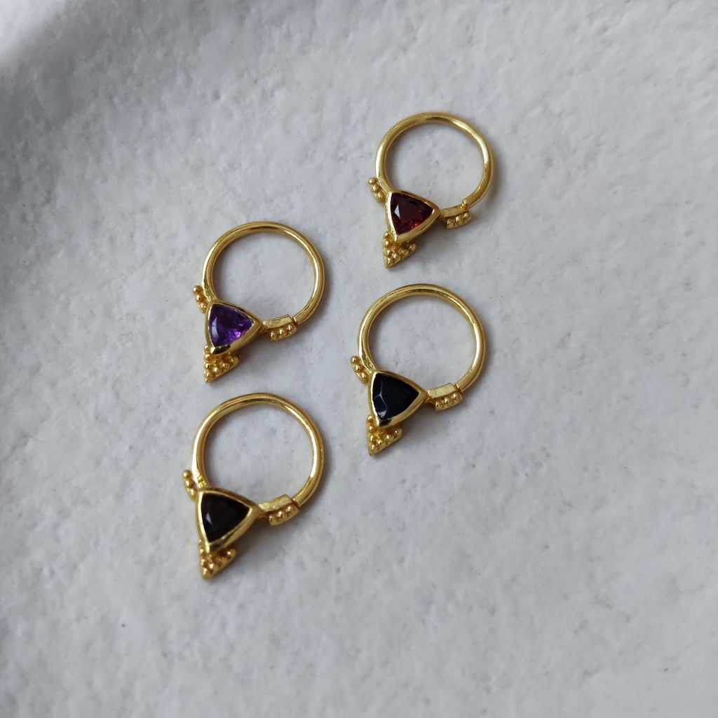 Four pieces of gold septum jewelry with various gemstones
