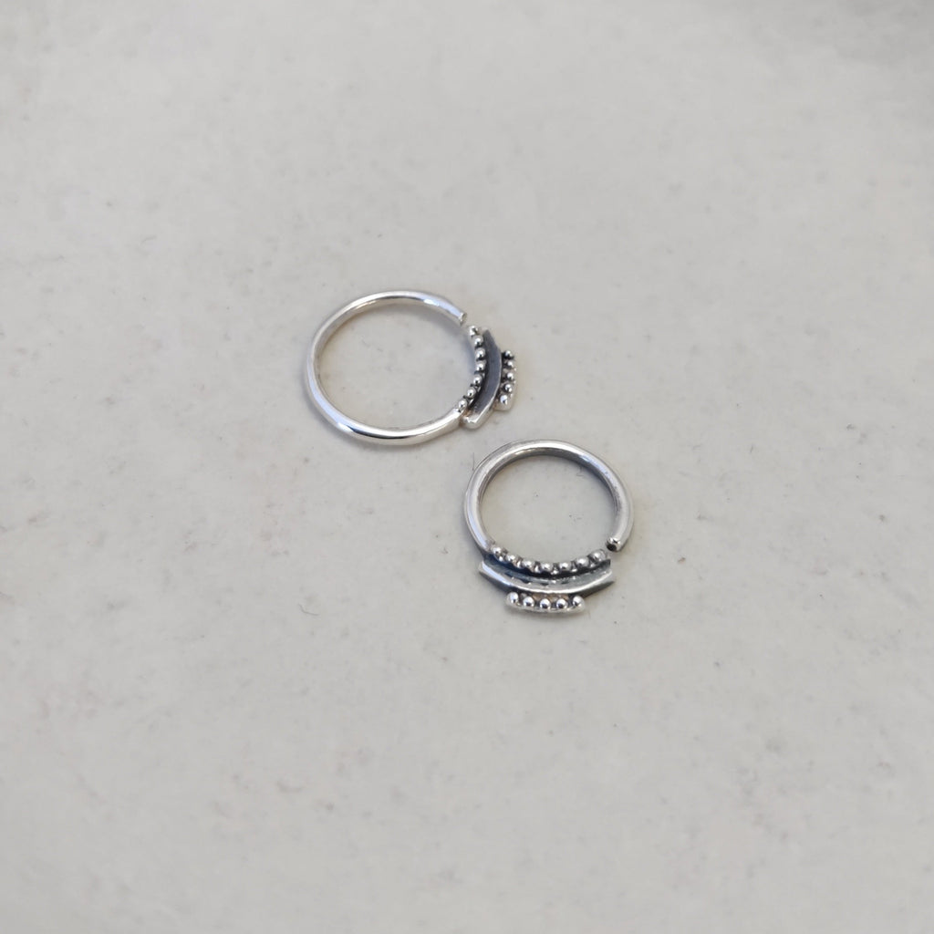 Dainty silver septum rings with intricate detailing, comparing the difference between 8mm and 10mm diameters and highlighting its unique design.