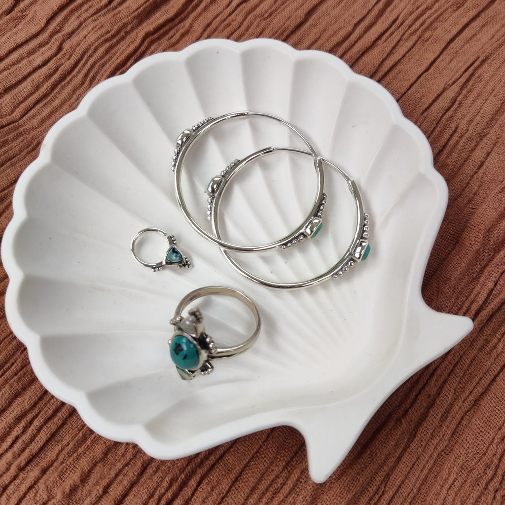 Unique silver hoop earrings featuring intricate dotted details and turquoise, turquoise ring and septum nose ring, displayed on a jewelry dish.