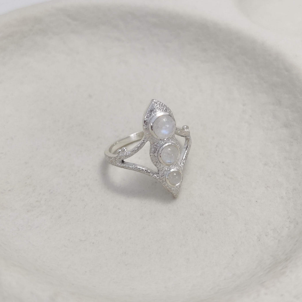 Bohemian silver ring with three moonstones on a white ceramic dish.