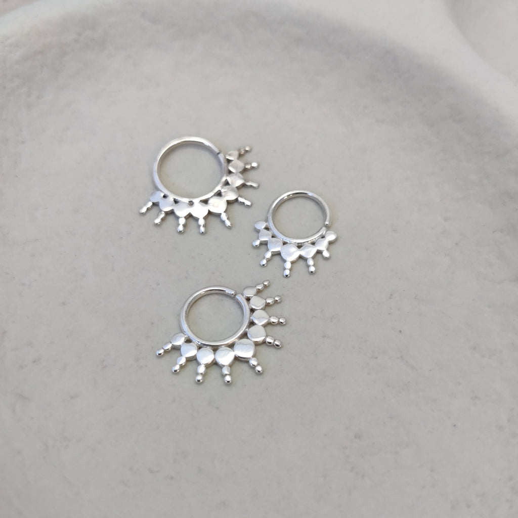 Ornamental silver septum rings with intricate detailing, highlighting its unique flat design.