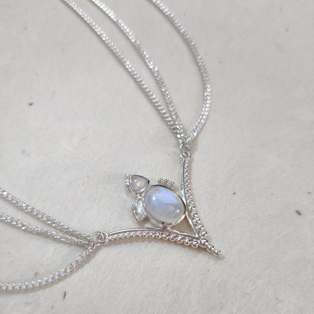 Silver head chain with a moonstone  and opal pendant on a light background