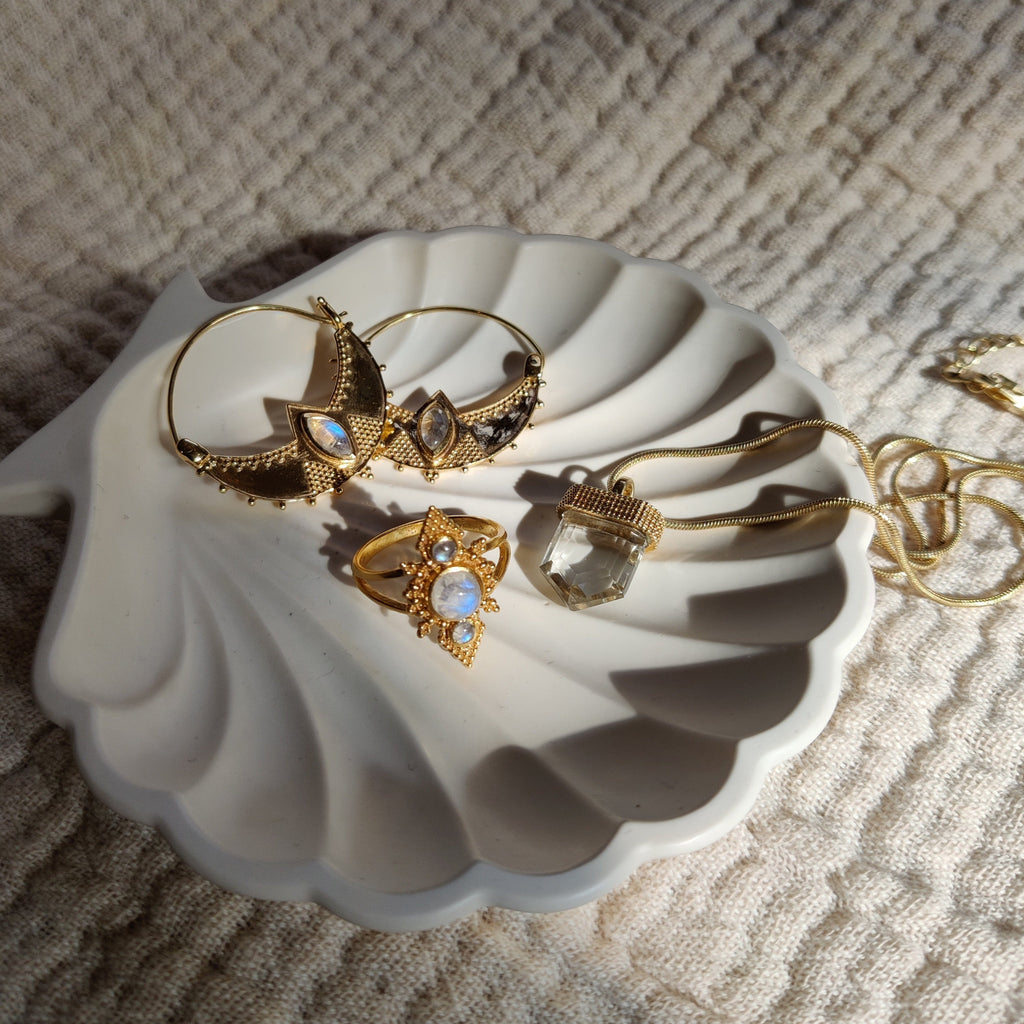 Moonstone earrings and ring, quartz necklace, displayed on a jewelry plate.