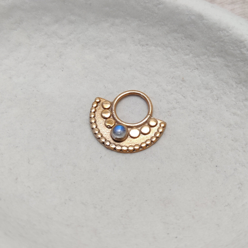 Gold septum with moonstone, displayed on a jewelry plate. Sacred Septum.