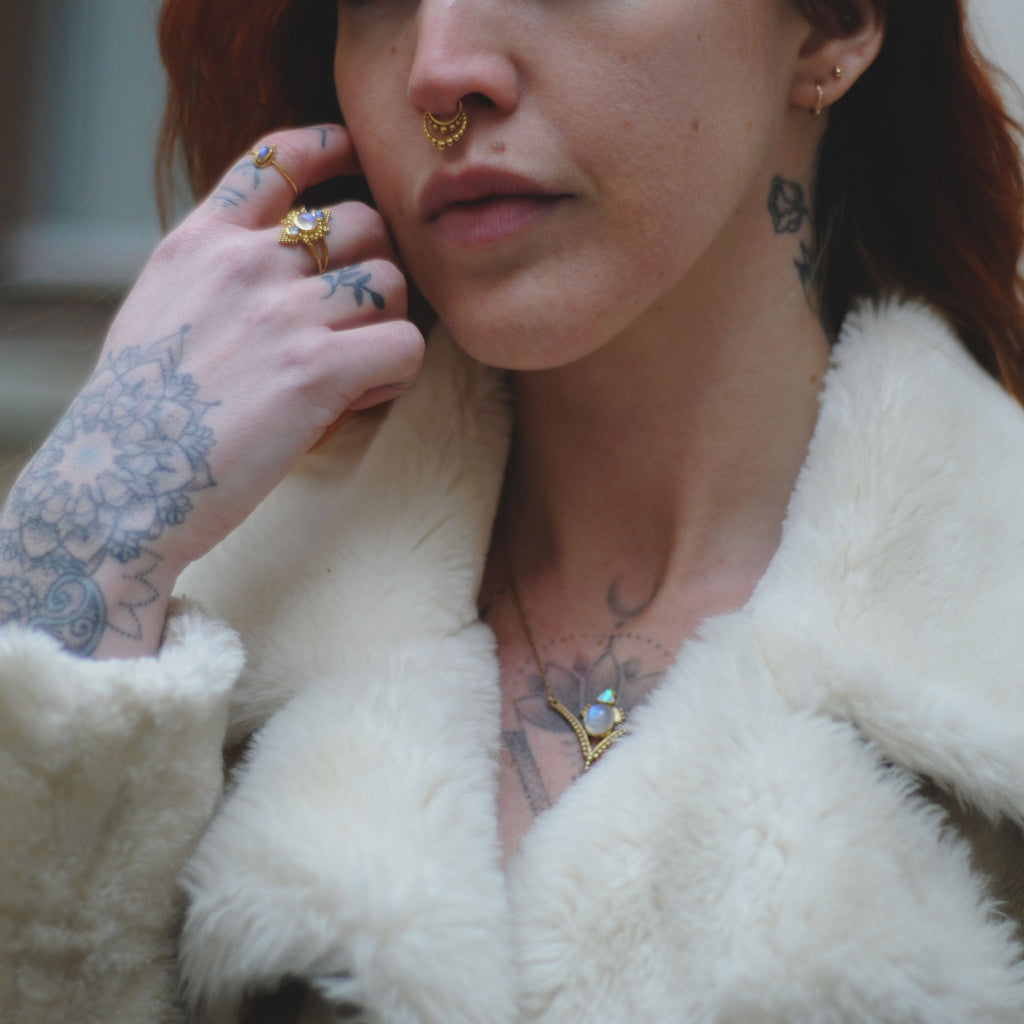 Brass rings and necklace with moonstone, worn on a model.