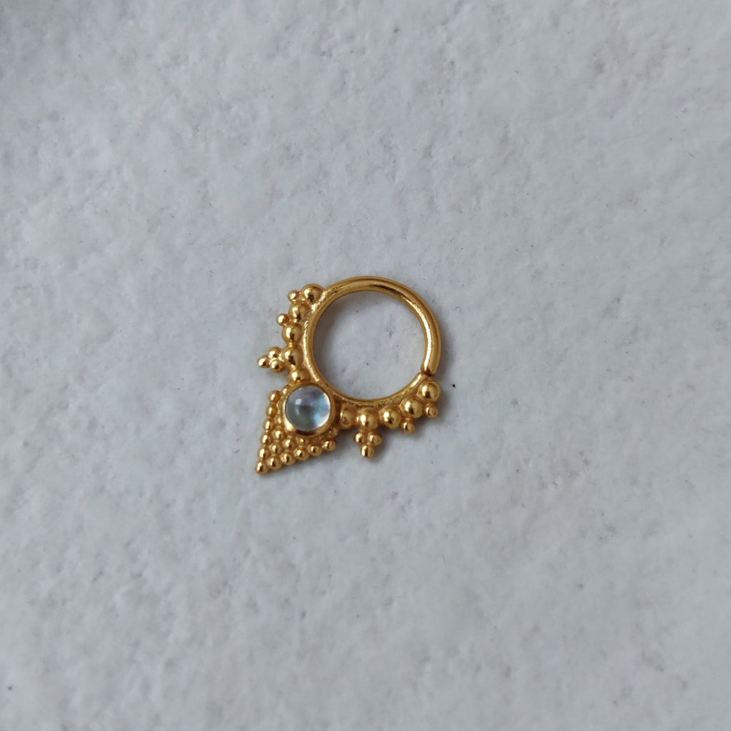 A V-shaped gold septum ring inspired by ancient jewelry, with dotted details and a moonstone centerpiece.