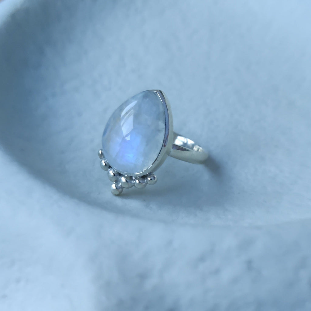 Silver ring with moonstone, displayed on a jewelry plate.