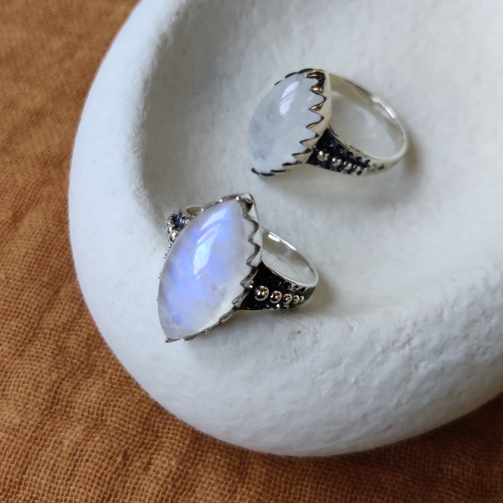 Silver rings with moonstone, displayed on a jewelry plate.