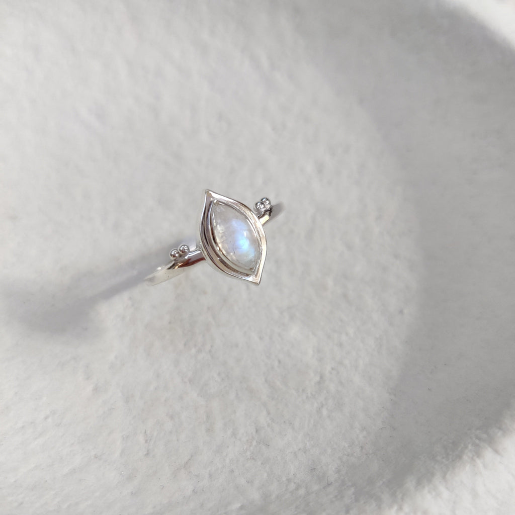 Silver ring with a moonstone on a textured white surface