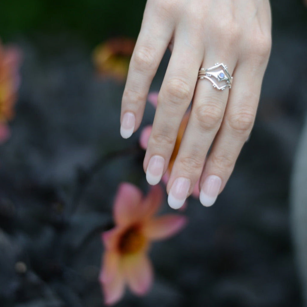 Hand with three stacking rings on a blurred natural background.