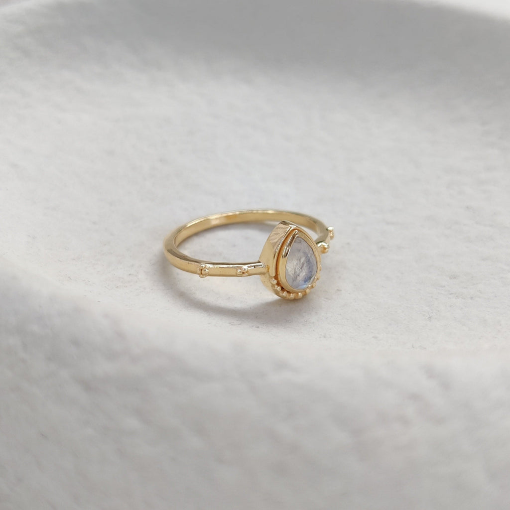 Gold ring with a clear gemstone on a white surface.