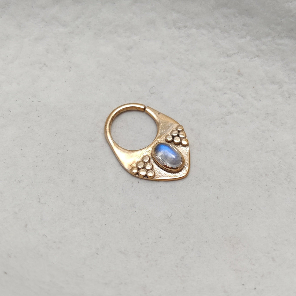 Triangle gold septum with moonstone, displayed on a jewelry plate.