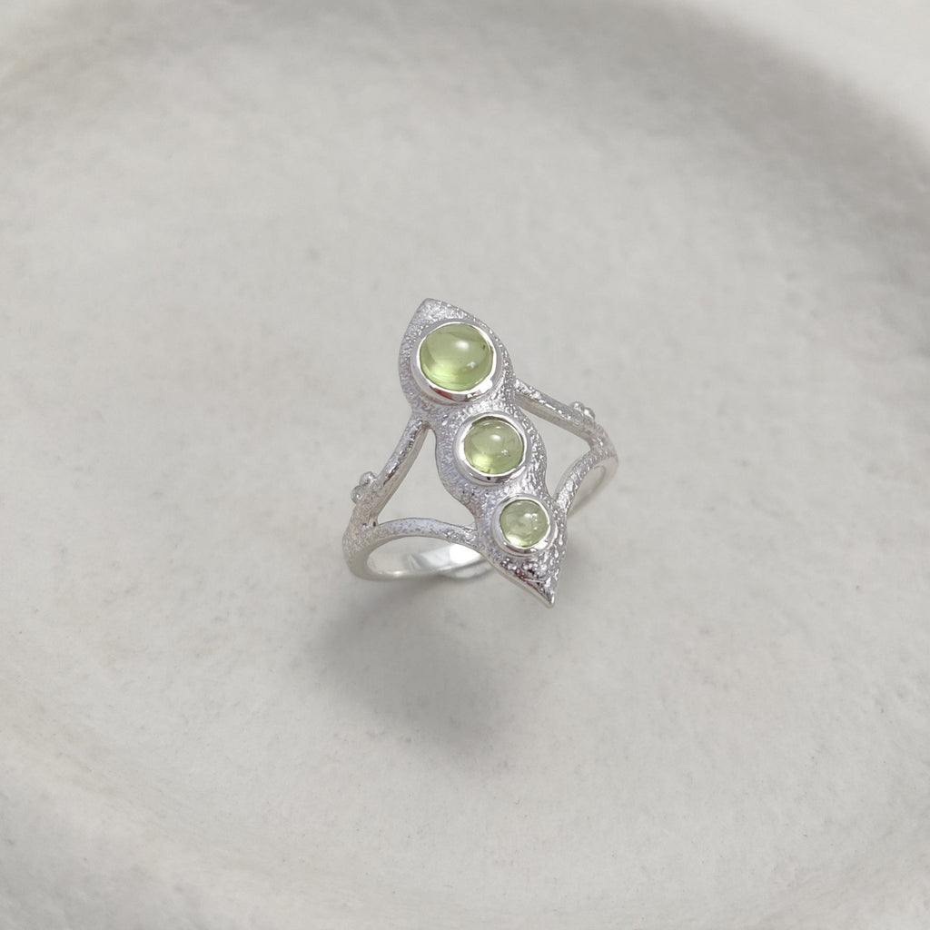 Bohemian silver ring with three green gemstones on a white surface.