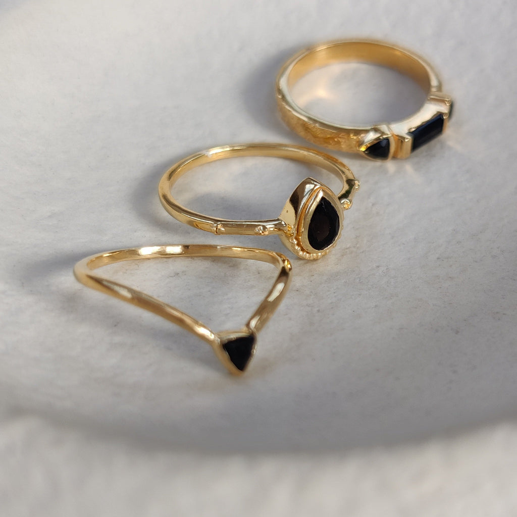 Three gold rings with black onyx gemstones on a white background