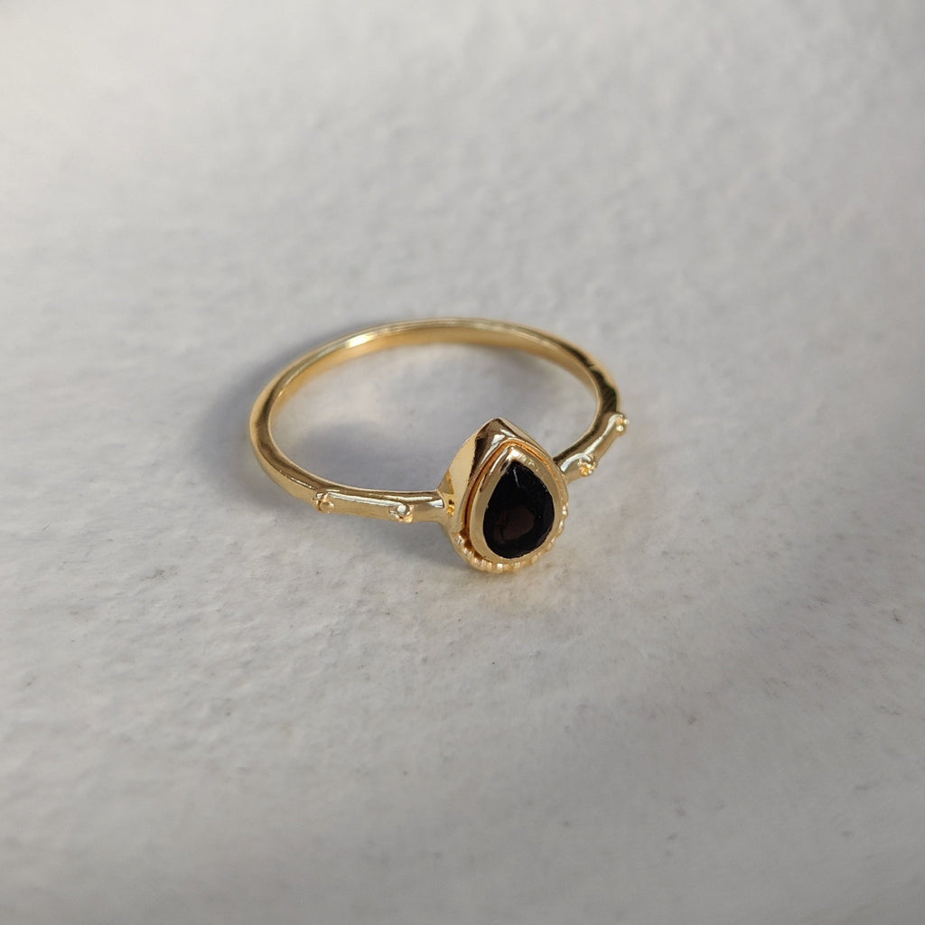 Gold ring with a black gemstone on a white background
