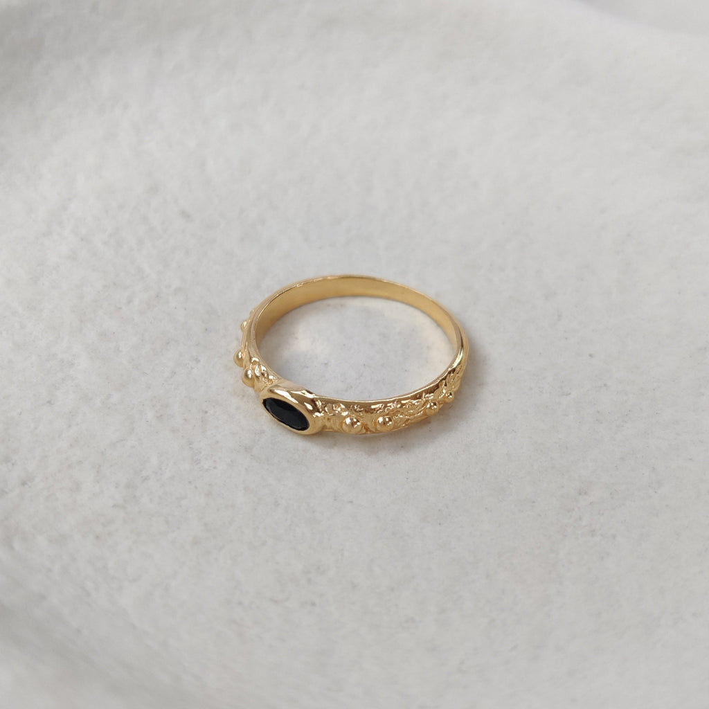 Gold ring with a black gemstone on a white background.