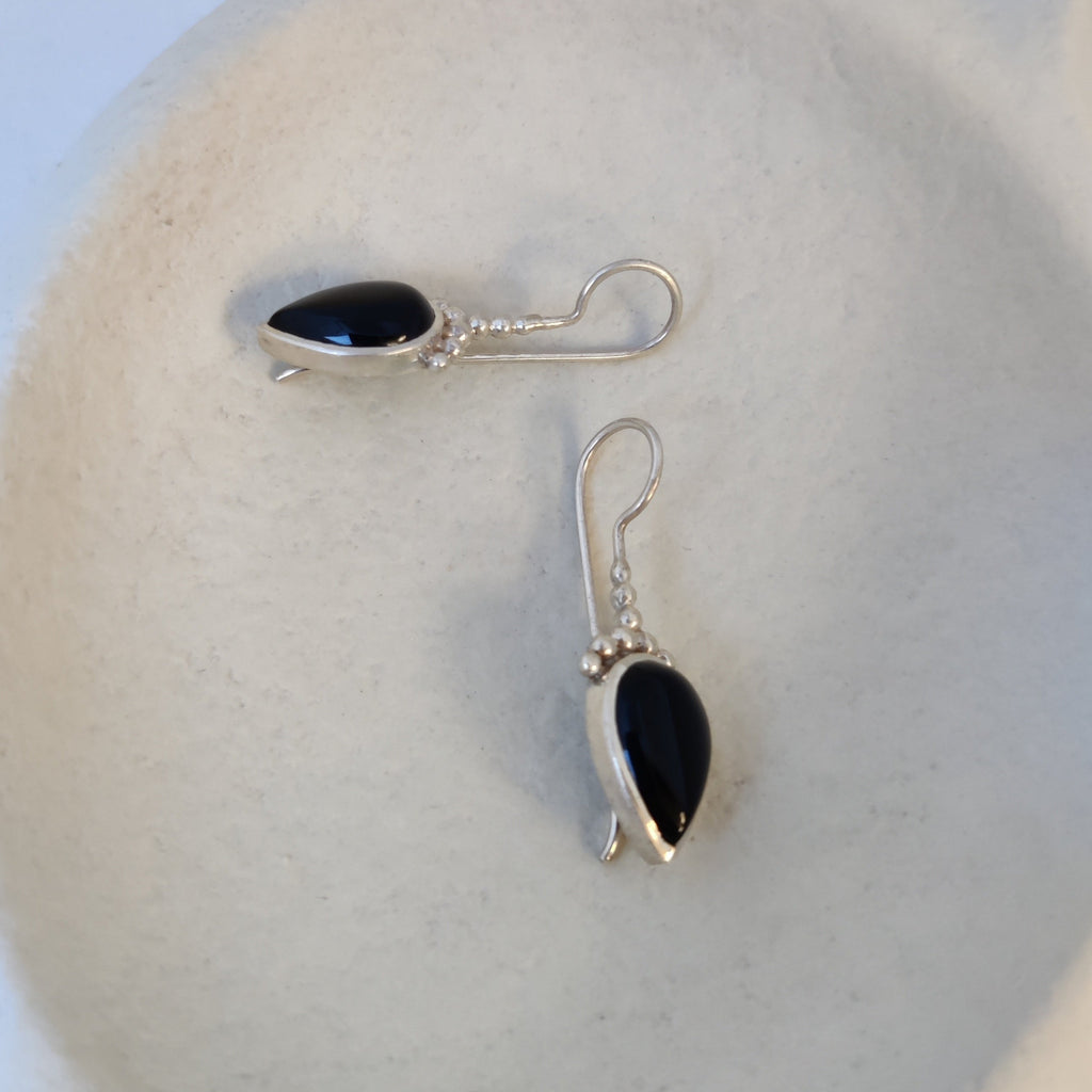 Silver hook earrings with black onyx, showcased from various angles, highlighting their unique design.
