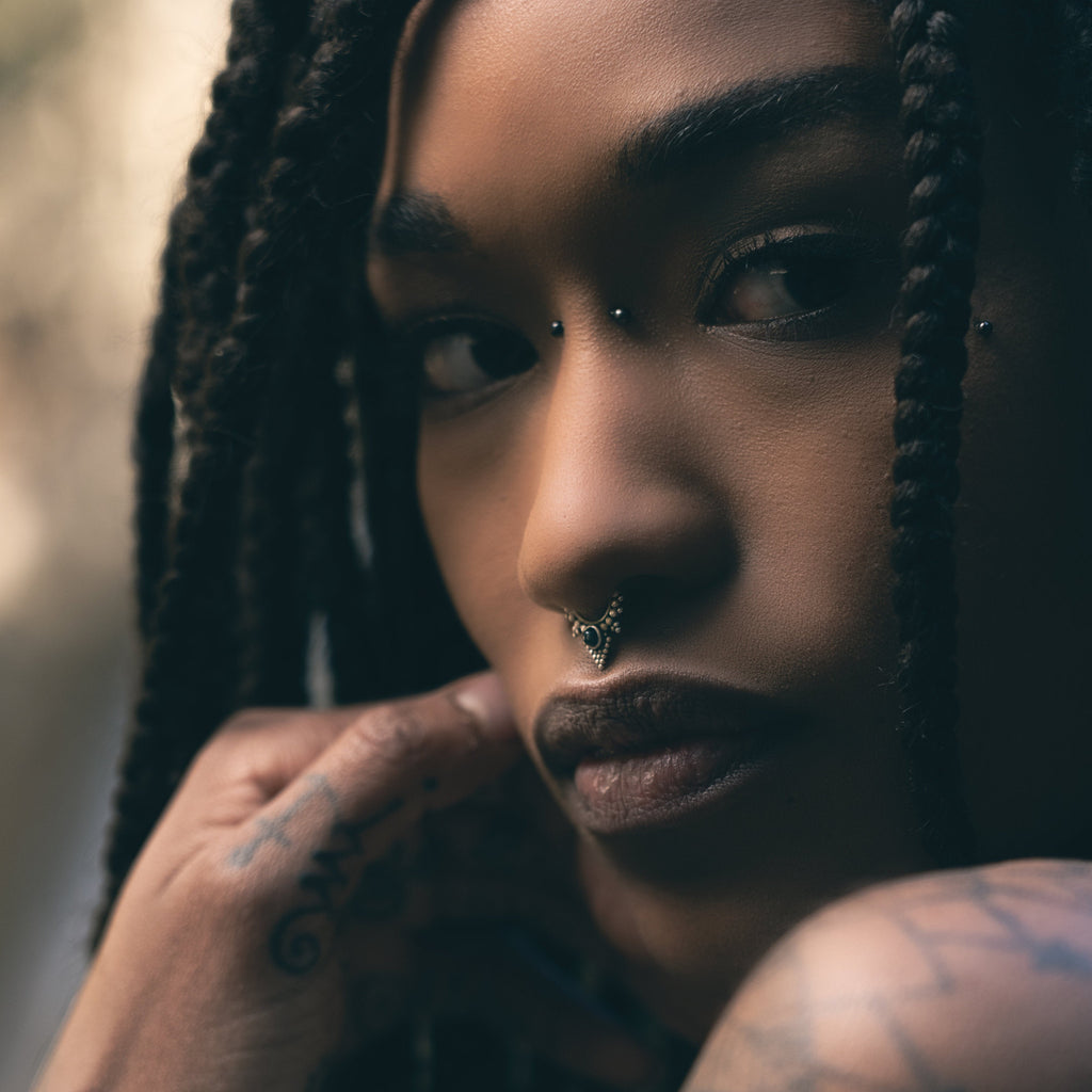 A model wearing a silver septum nose ring with black onyx, captured from the side.