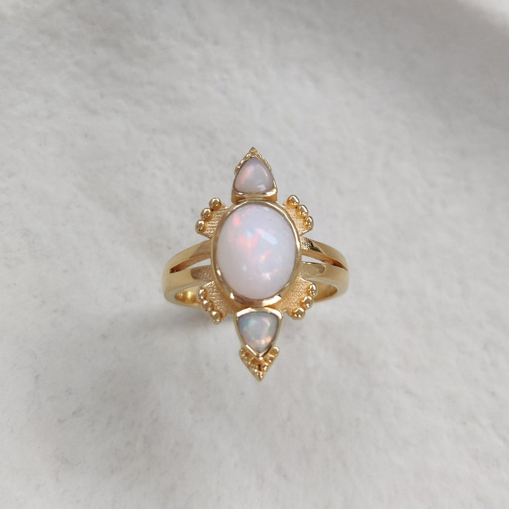 Gold ring with three opal stones on a white  background.