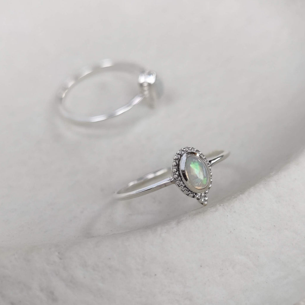 Silver ring with a opal gemstone on a white surface.