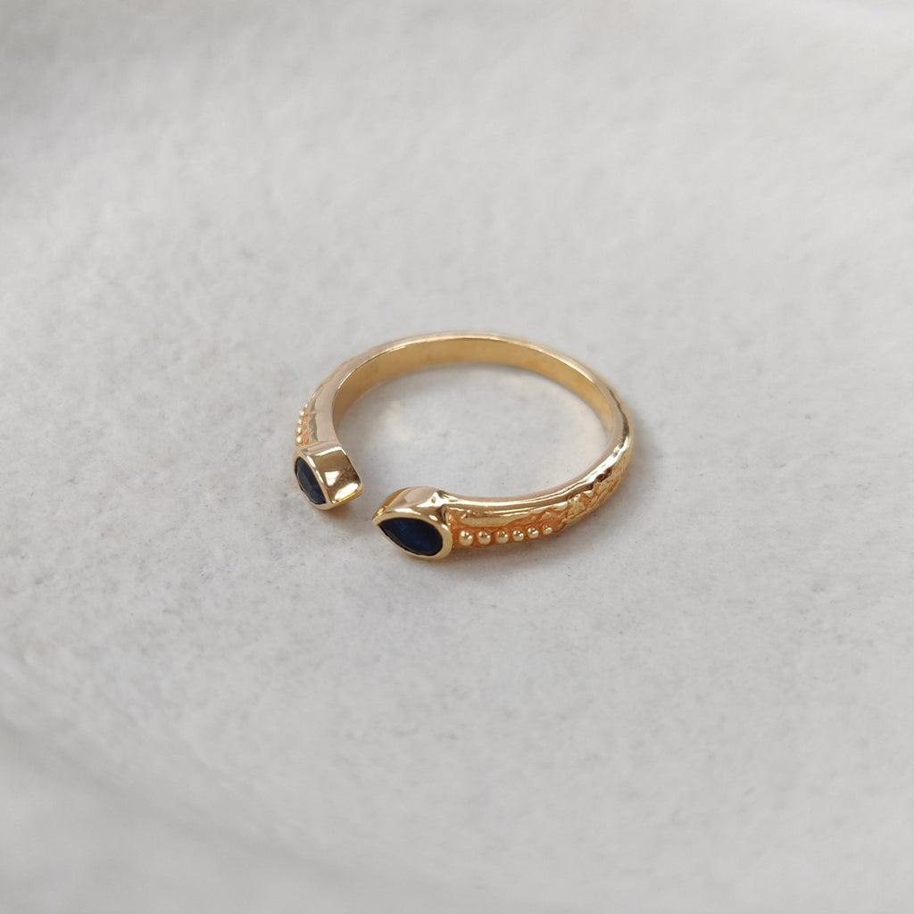 Gold ring with black sapphire on a white background.