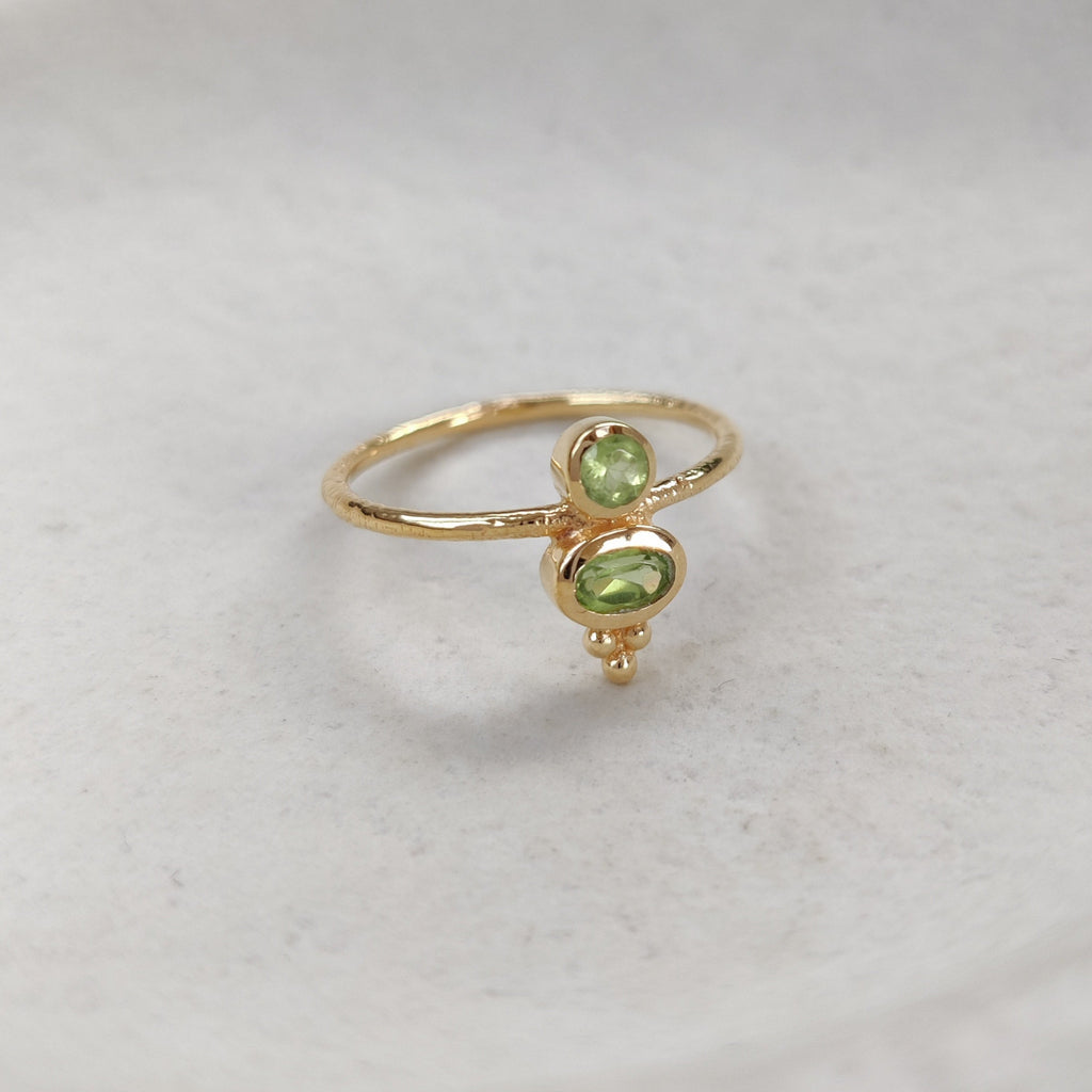Gold ring with green gemstones on a white background.