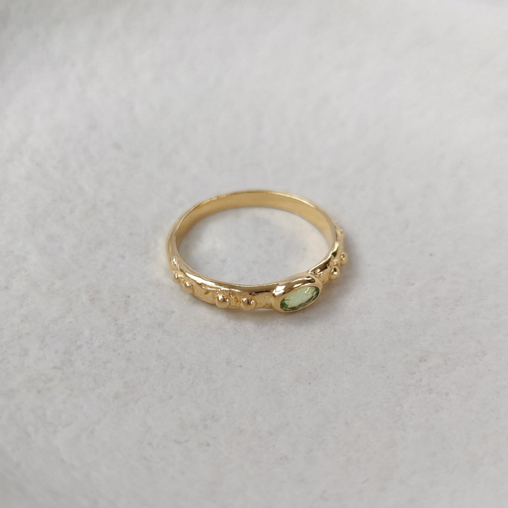 Gold ring with a green gemstone on a white background.