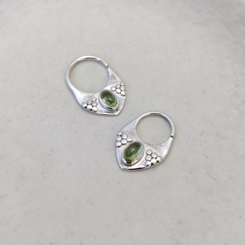 Silver septum rings with peridot, displayed side by side, highlighting intricate designs.