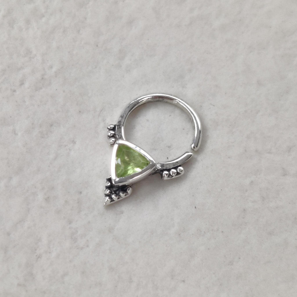Silver septum nose ring with a green gemstone.