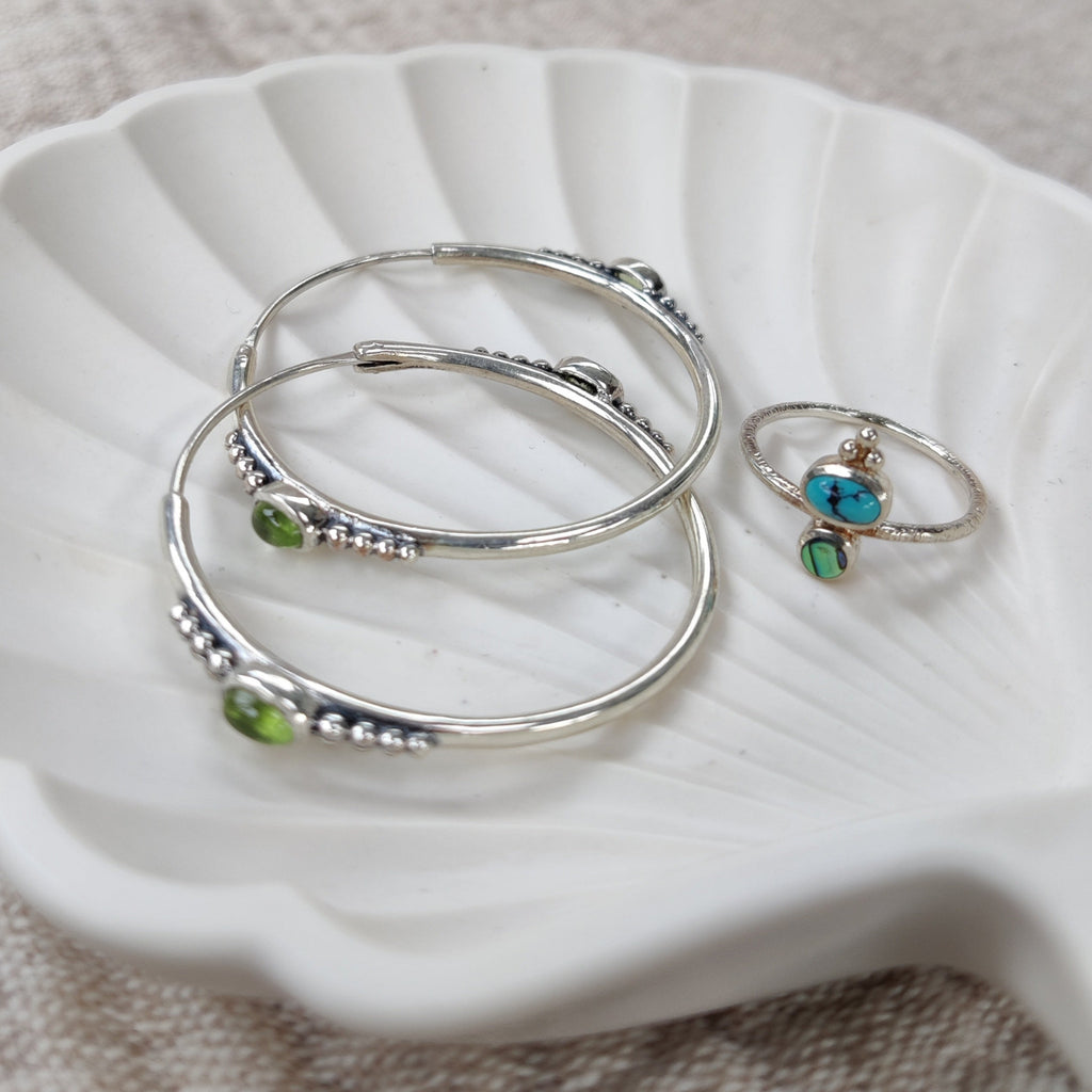 Unique silver hoop earrings featuring dotted details and peridot, and dainty turquoise ring.