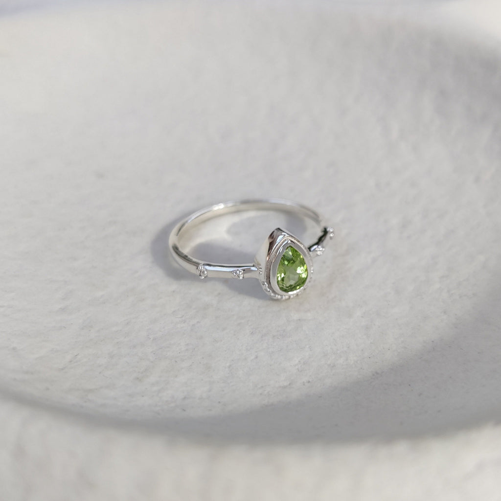 Silver ring with a green gemstone on a white background