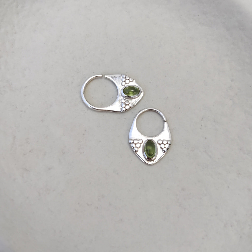 Silver septum jewelry with peridot, displayed side by side, showcasing the unique design from different angles.