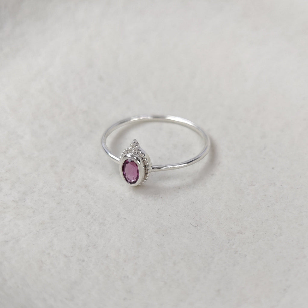 Silver ring with a pink gemstone on a light background