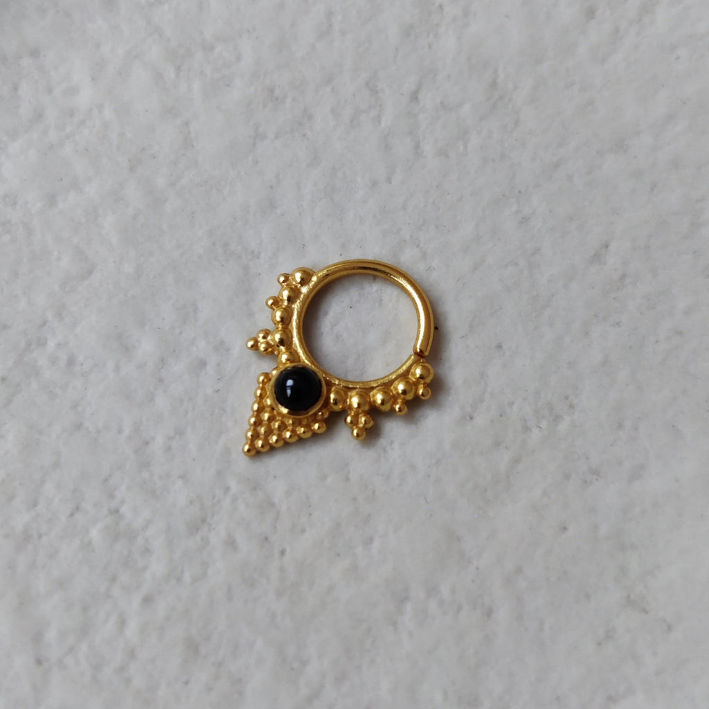 A V-shaped gold septum ring inspired by ancient jewelry, with dotted details and a onyx centerpiece.