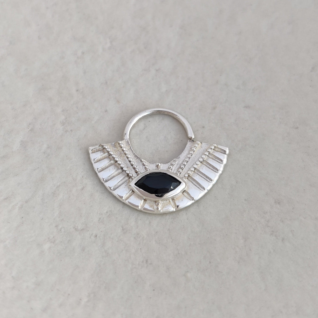 Large silver septum nose ring with a black gemstone on a light background