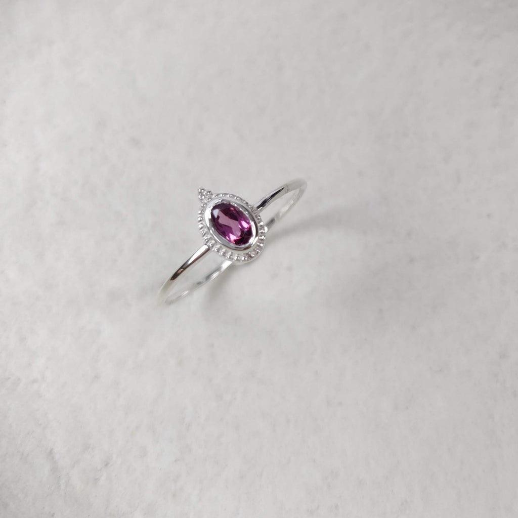 Silver ring with a pink gemstone on a white background