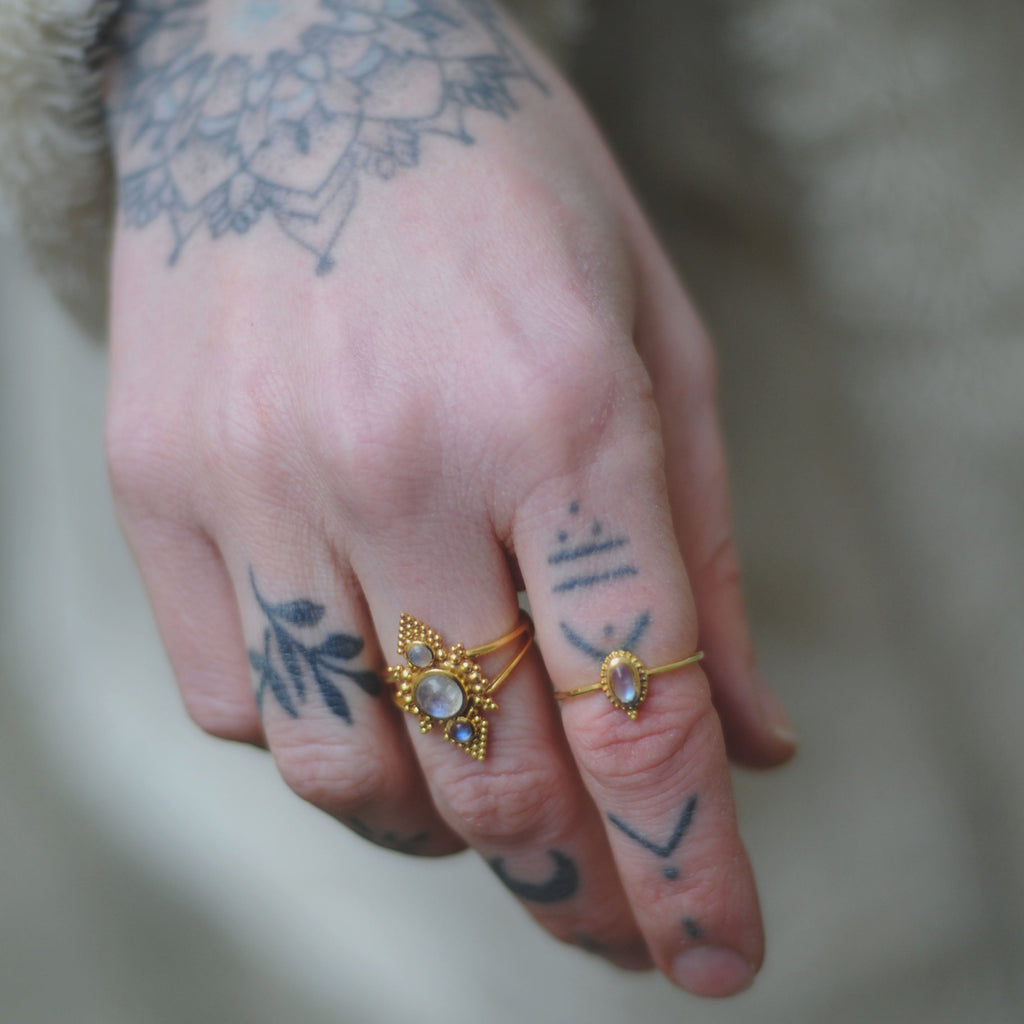 Brass rings with moonstone, worn on a hand.