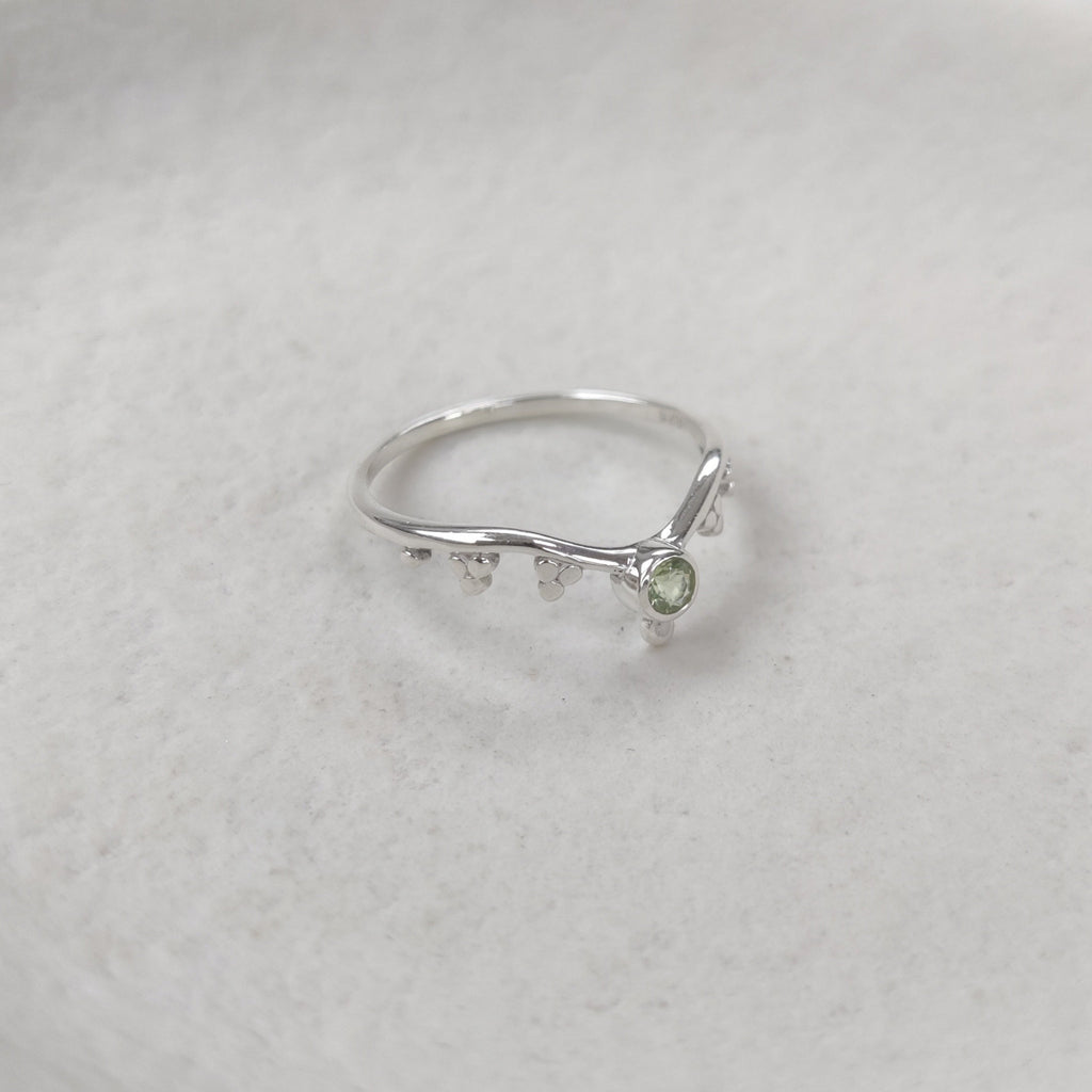 Silver stacking ring with a green gemstone on a white background.