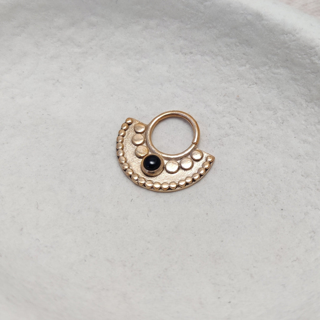 Gold septum with black onyx, displayed on a jewelry plate.