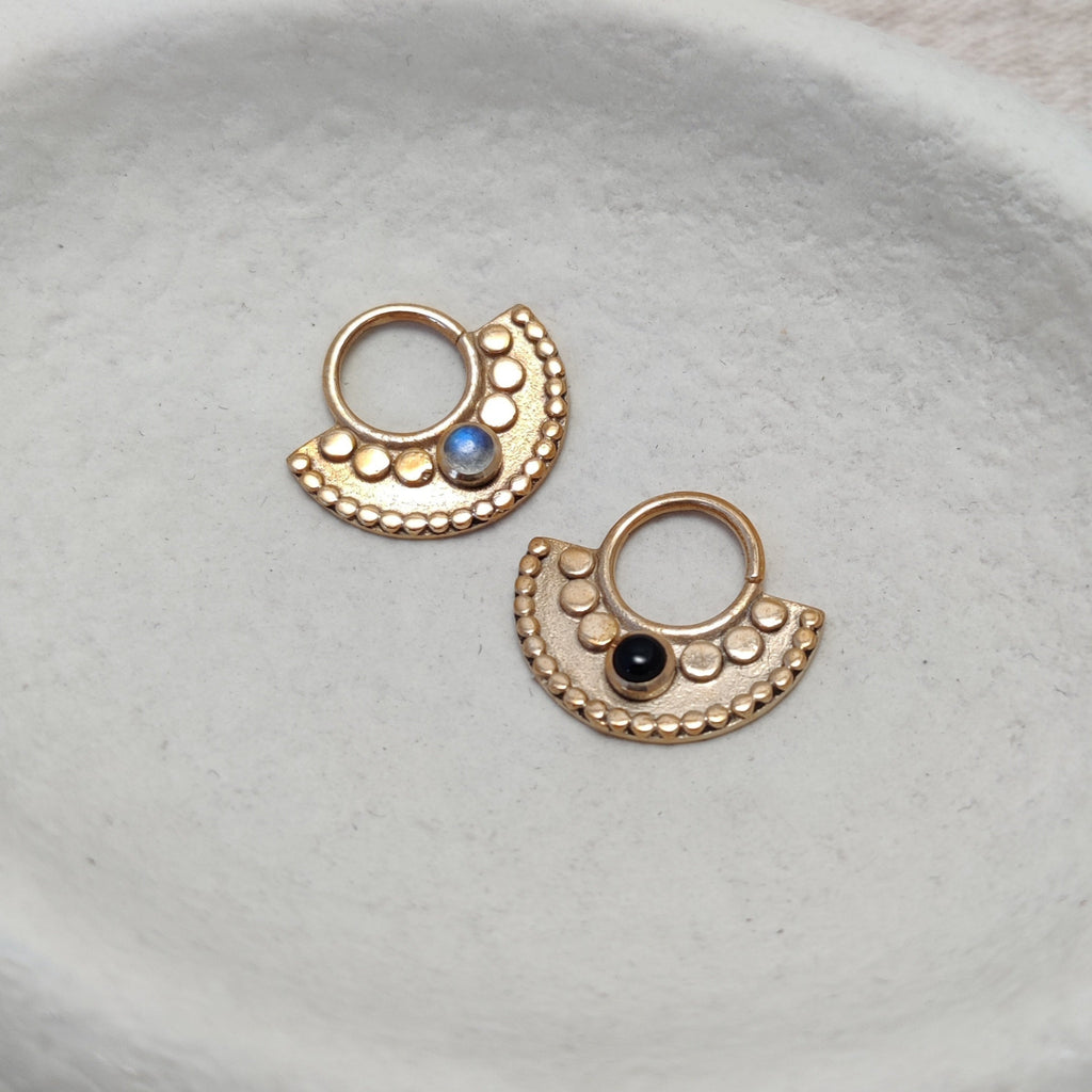 Large tribal septum rings, gold with moonstone or black onyx, displayed on a jewelry plate.